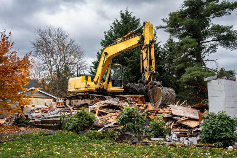 house demolition contractor - Excavator completing demolition of a house for residential re-development, large pile of debris ready for removal