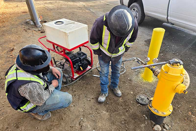 hydrostatic pressure testing - Field crew conducts hydrostatic pressure test on municipal watermain using hydrant-mounted pressure gauge and portable test pump.